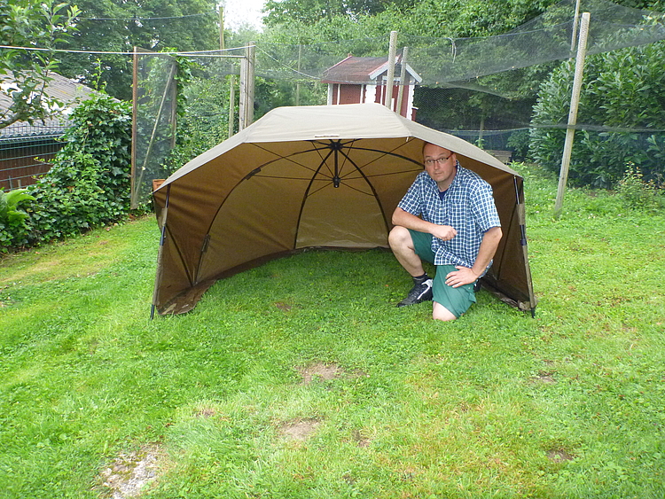 Mann kniet im Wetterschutz (Zelt)